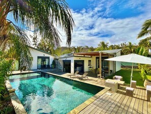 A modern pool area with a clear pool, wooden deck, and outdoor seating. - *VILLA RAVENALE* - Ocean 150 m away (Saint-Paul)