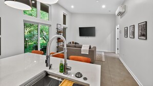 A modern kitchen with a large island, a built-in oven, and a window overlooking greenery. - 500 House - Unit A 1 Bedroom Townhouse (Mequon)