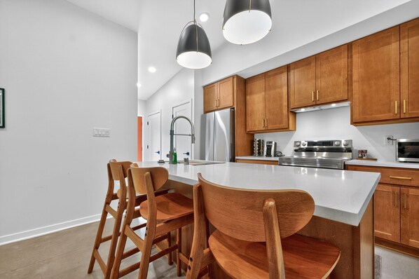 A modern kitchen with wooden cabinets, stainless steel appliances, and a central island with bar stools.