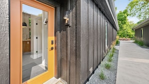 A modern building with a dark exterior, a wooden door, and a small outdoor seating area. - 500 House - Unit A 1 Bedroom Townhouse (Mequon)