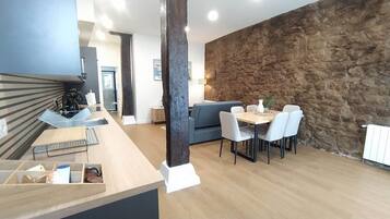 A modern kitchen with a built-in stove, a dining area with a stone wall, and a seating area with a sofa.