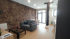A modern lobby with a stone wall, a grey sofa, a wooden coffee table, and a reception desk.