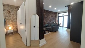 Een moderne woonkamer met een stenen muur, een bank, een salontafel en een deur naar een andere kamer.