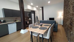 A modern kitchen with a dining area, a small refrigerator, and a television.