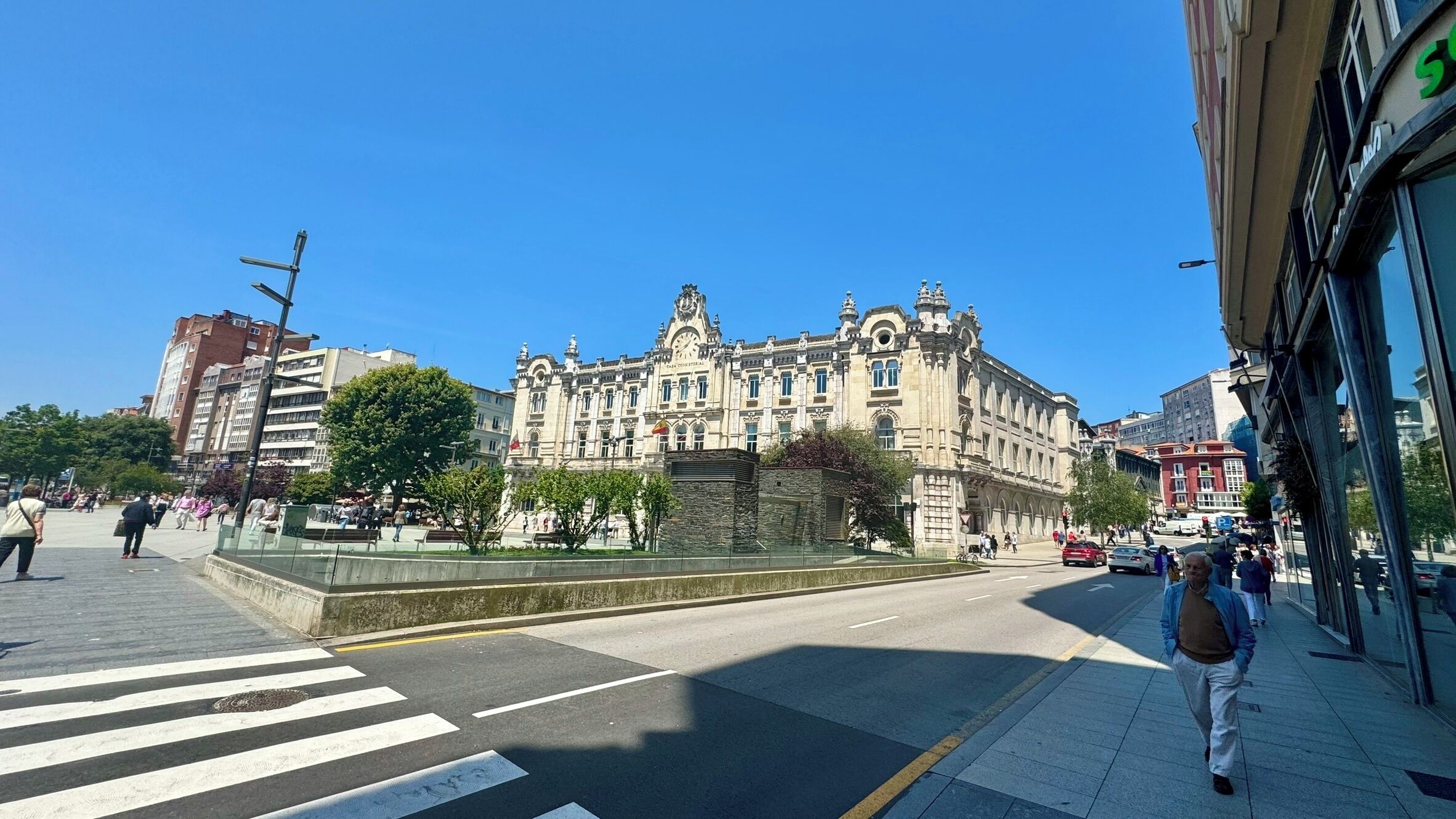 A historic building with classical architecture, a pedestrian crossing, and a clear blue sky.