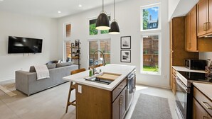 A modern kitchen with a central island, wooden cabinets, and a large window. - 500 House - Unit C 1 Bedroom Townhouse (Mequon)
