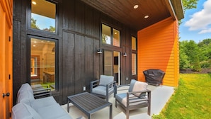 A modern outdoor patio with a dining set and chairs, a grill, and a view of the interior through large windows. - 500 House - Unit D 2 Bedroom Townhouse (Mequon)