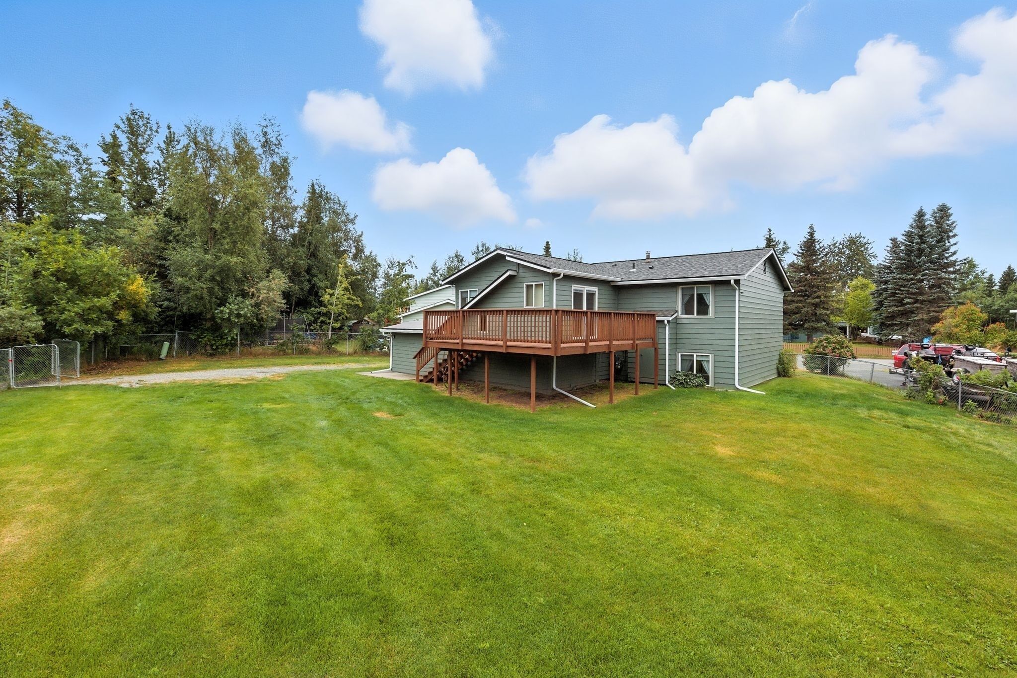 A two-story house with a wooden deck and a fenced yard.