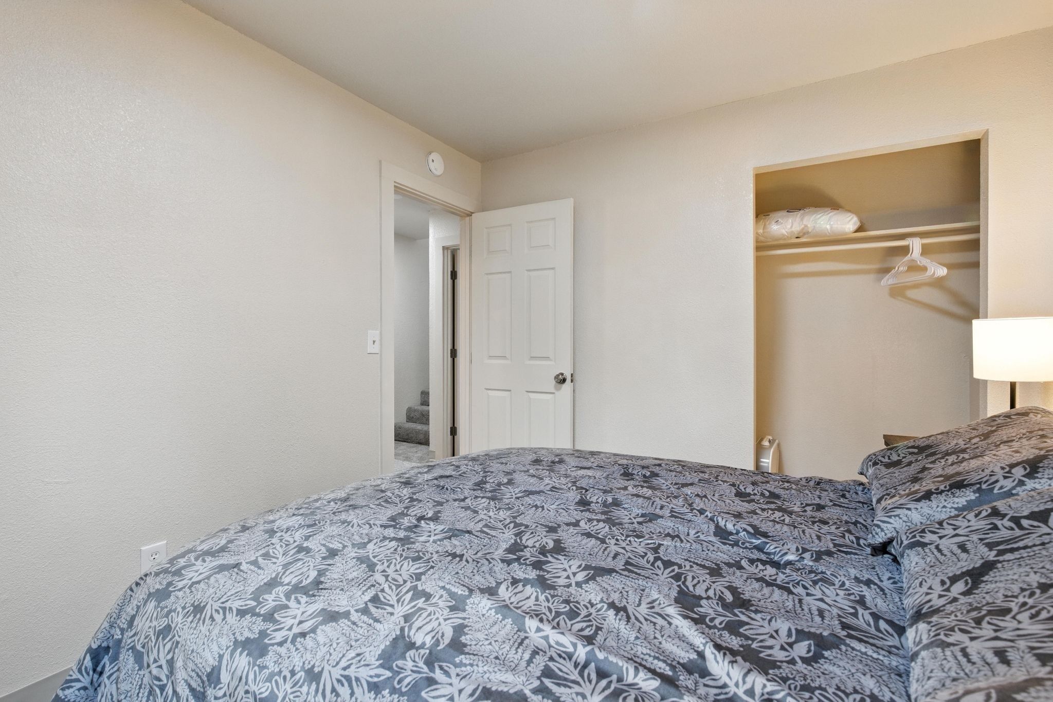 A bedroom with a bed, a closet, and a nightstand.