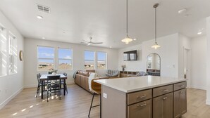 Une cuisine spacieuse avec un grand îlot central, un coin repas avec une table et des chaises, et un espace détente avec un canapé et des fauteuils.