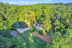 A secluded property surrounded by dense forest, featuring a main house, a smaller structure, and a fenced area. - The Sassafras - Shipping Container, shared Hot Tub (Easley)