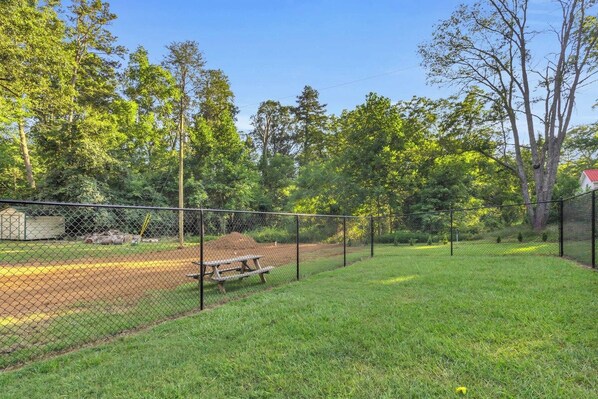 A fenced outdoor area with a picnic table and a baseball diamond. - The Sassafras - Shipping Container, shared Hot Tub (Easley)