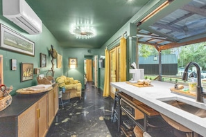 A kitchen with a bar area, a dining table, and a window with a view of the outdoors. - The Sassafras - Shipping Container, shared Hot Tub (Easley)
