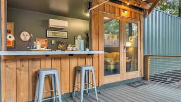A bar area with two stools, a wooden counter, and a glass door leading to an outdoor space.