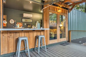 Un coin bar avec deux tabourets, un comptoir en bois et une porte vitrée donnant sur un espace extérieur.