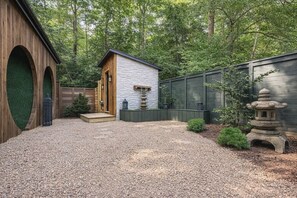 Un patio de grava con una estructura de madera, un edificio de piedra y una valla de madera.