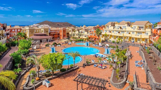 A resort with a large central pool, multiple swimming pools, and a variety of sun loungers and umbrellas.