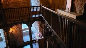 A rustic interior with stone walls, a wooden staircase, and a loft area with a bed. - Burg Hermannstein - Rittersaal  (Wetzlar)