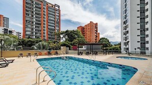 Ein Pool auf dem Dach mit einer gefliesten Liegefläche, umgeben von Liegestühlen und einer kleinen Bar.