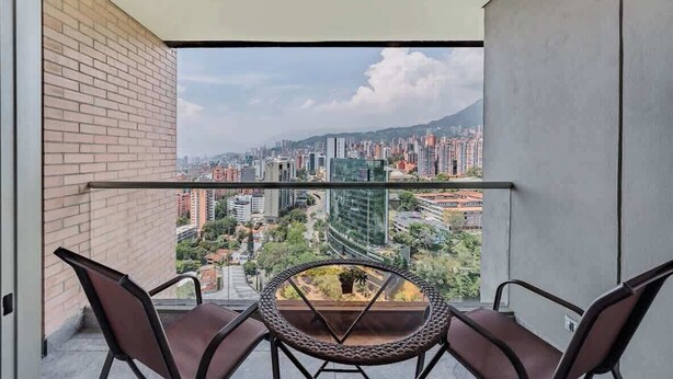 Ein Balkon mit Blick auf eine Stadtlandschaft, einschließlich Gebäude und ein Berg in der Ferne.