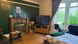Una habitación con chimenea, televisión, cama y ventana con vistas a follaje.