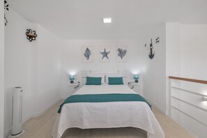 A bedroom with a bed, bedside tables, wall art, and a ceiling light.