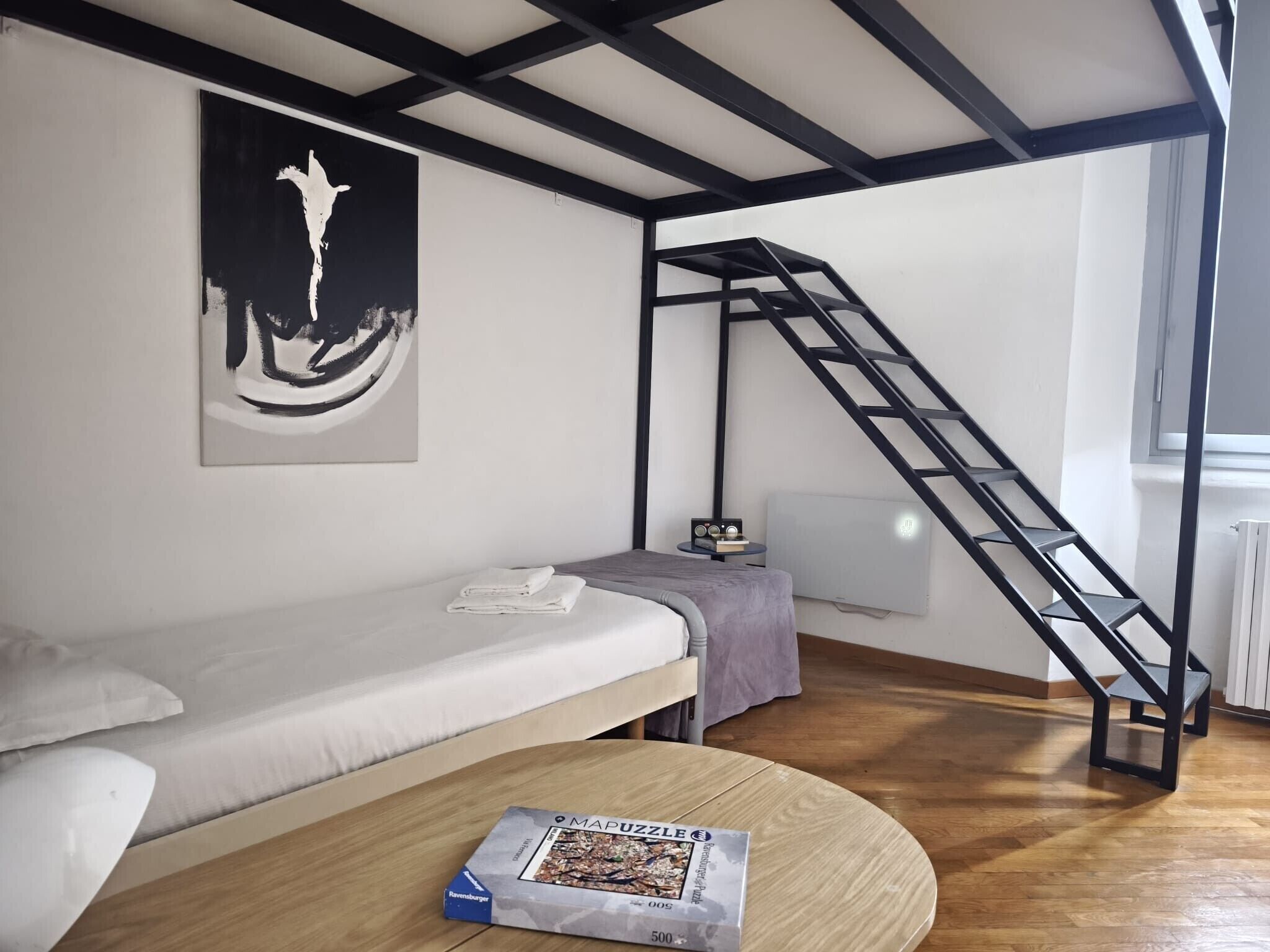 A room with a bunk bed, a small table with a puzzle, a radiator, and a ladder.