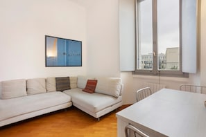 A modern living room with a sofa, a dining table, and a large window. - Quiet, Modern Apartment in CityLife, Close to the Center (Milano)