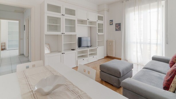 A modern living room with white cabinetry, a grey sofa, and a television.