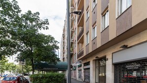 A multi-story building with balconies, a covered outdoor seating area, and a storefront with a metal gate.