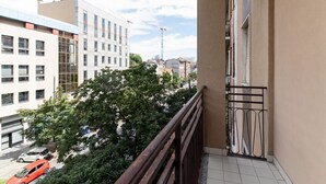 A balcony with a view of a cityscape, including buildings and trees.