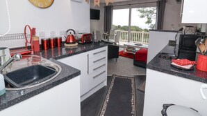 A modern kitchen with a large clock, a dining area with a view, and nautical-themed decorations. - I C Lundy Too (Bideford)