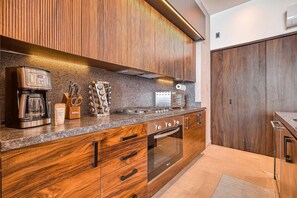 Una cocina moderna con armarios de madera, una cafetera, un tostador y un horno empotrado.