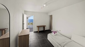 A bedroom with a bed, a bedside table, a bench, and a view of the sea.