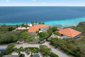 Um imóvel costeiro com vários edifícios, uma entrada pavimentada e vista para o oceano.