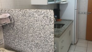 Une cuisine de taille réduite, avec des meubles blancs, un four à micro-ondes et un réfrigérateur.