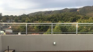 Un balcon avec vue sur une rivière et des collines.