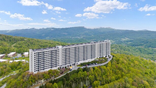 Ein mehrstöckiges Hotel mit Innenhof, umgeben von üppiger Vegetation und Bergen im Hintergrund.