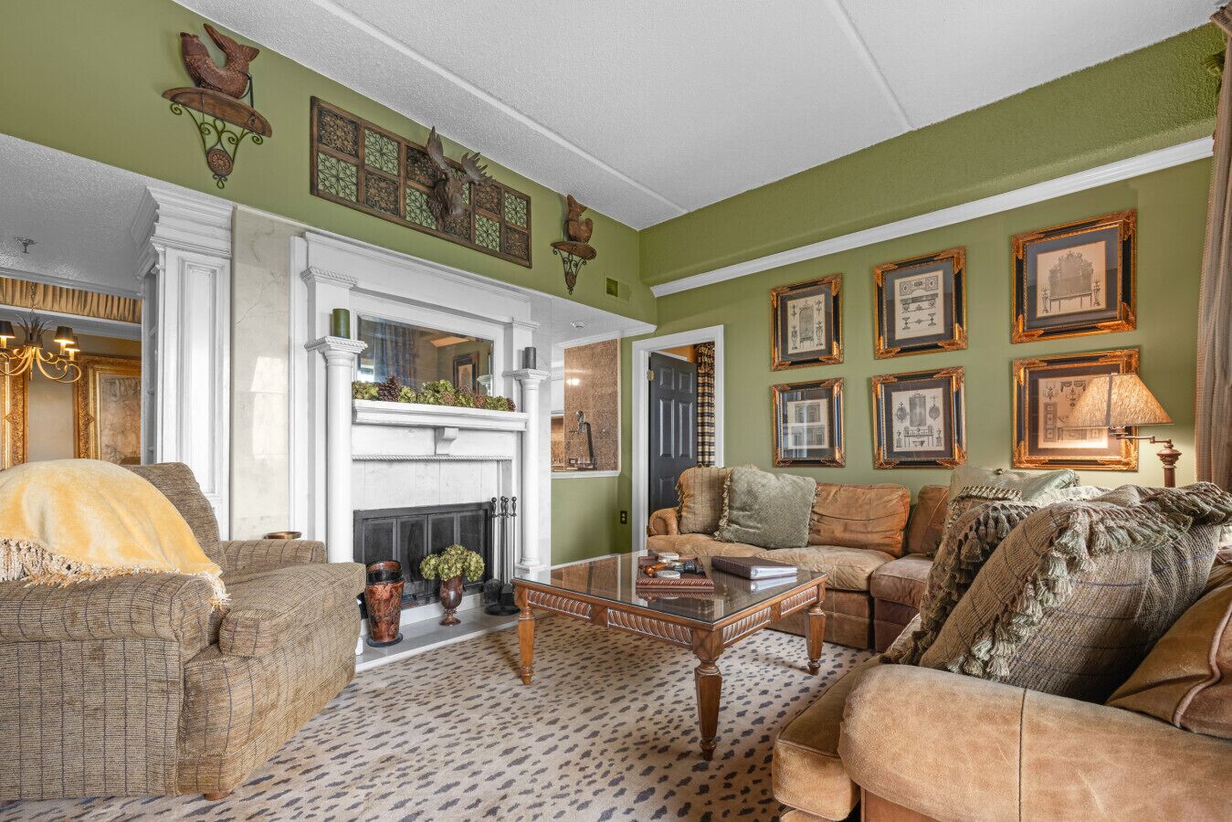 A traditional living room with a fireplace, comfortable seating, and framed artwork on the walls.