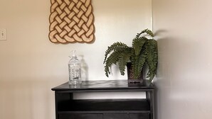 Een houten bureau met een plant en een glazen vaas erop.
