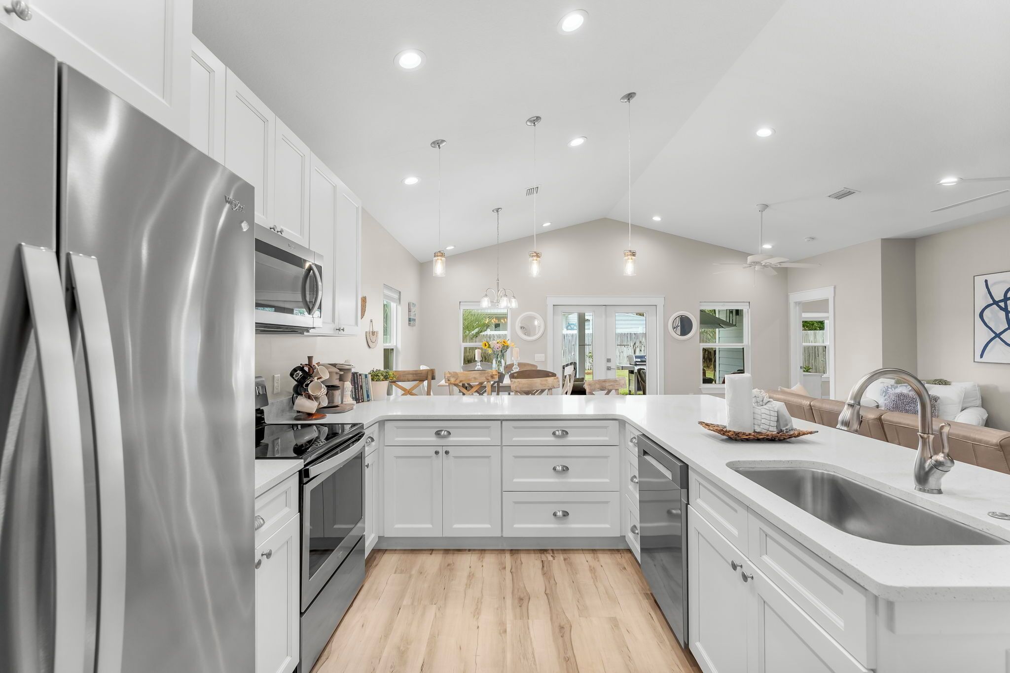 Et moderne køkken med hvide skabe, et rustfrit stål køleskab og en stor ø med vask.
