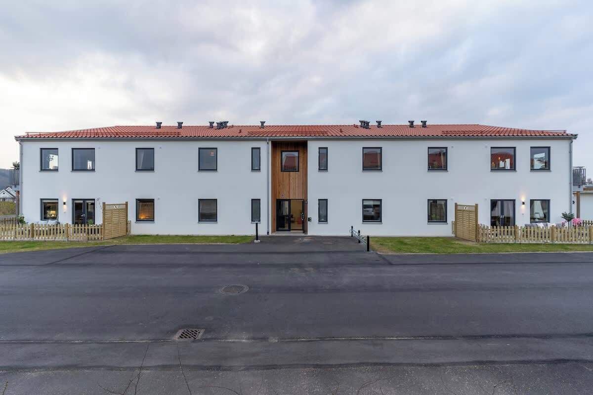 Un edificio a due piani con tetto in tegole rosse, diverse finestre e una porta centrale in legno.