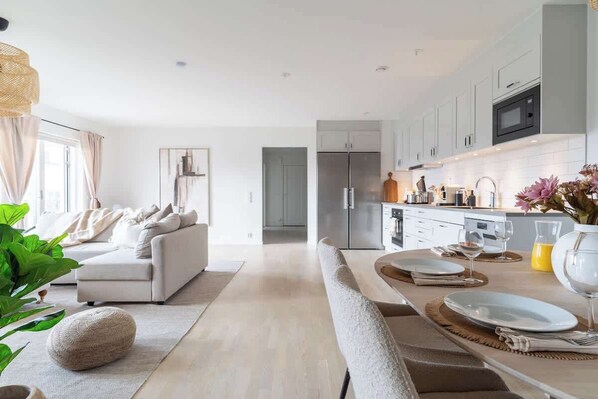 A modern kitchen with white cabinets, a built-in oven, and a stainless steel refrigerator.