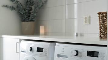 Un espace buanderie moderne avec deux machines à laver blanches et une plante en pot.