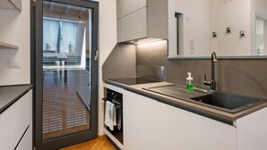Una cuina moderna amb rentaplats integrat, un rentamiques d'acer inoxidable i un rellotge a la paret.