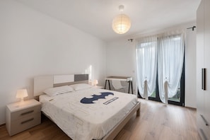 Un dormitorio con cama, mesitas de noche, un escritorio y una ventana con cortinas.