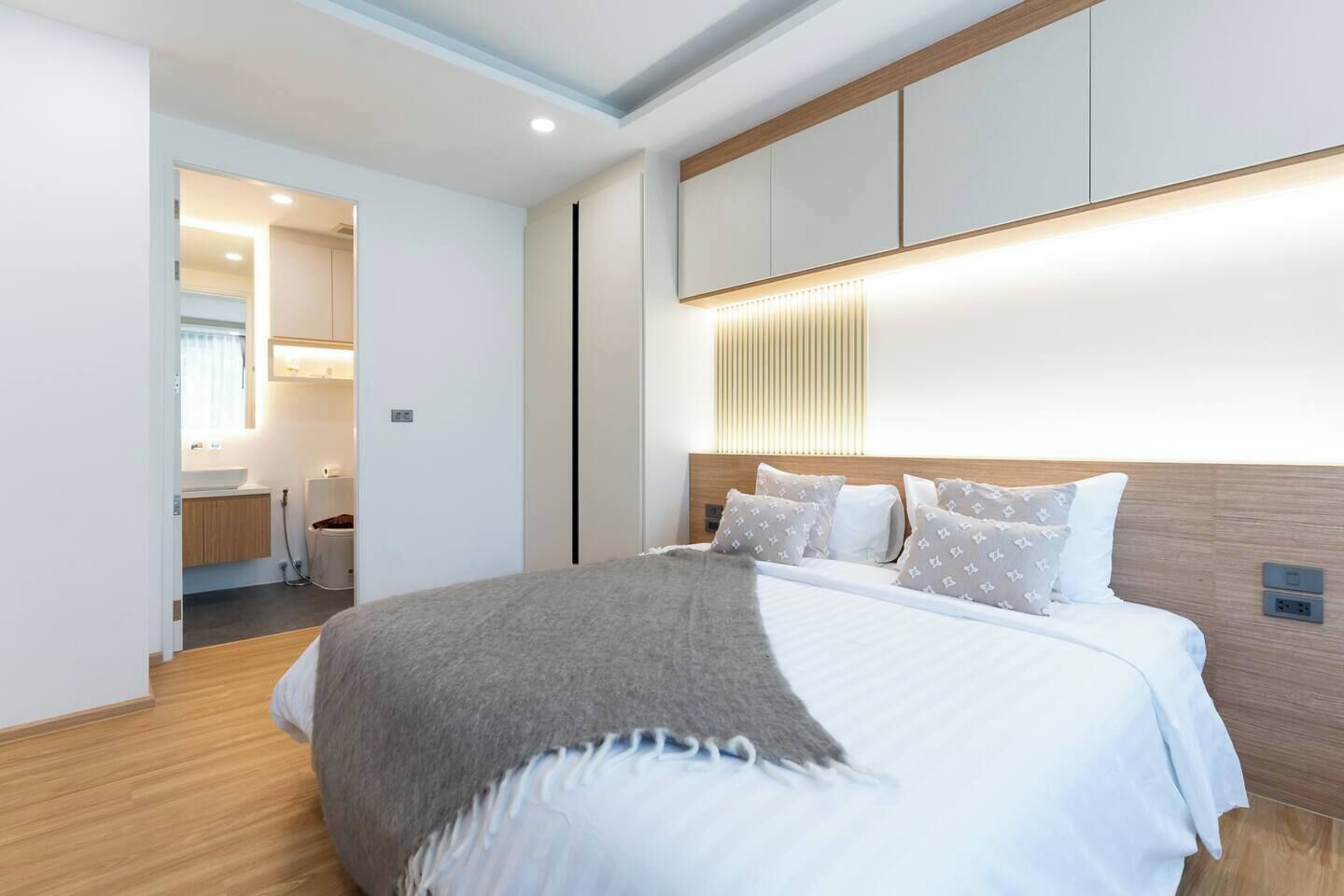 A modern hotel room with a large bed, a bedside table, and a built-in wardrobe.