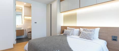A modern hotel room with a large bed, a bedside table, and a built-in wardrobe.