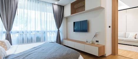 A modern bedroom with a bed, a TV, a built-in bench, and a view of a balcony.