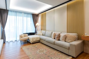 A modern living room with a sofa, armchair, and a patterned rug.